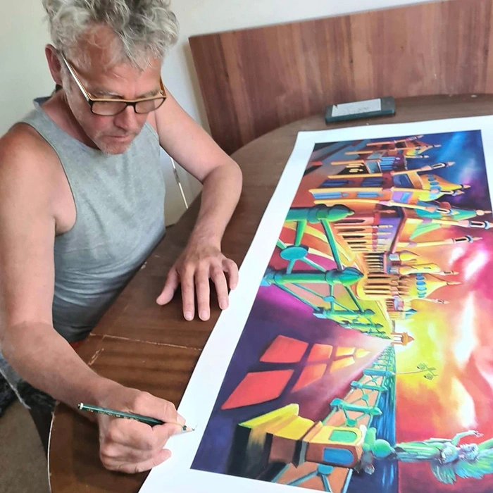 The artist signing a print that features Brighton Seafrount